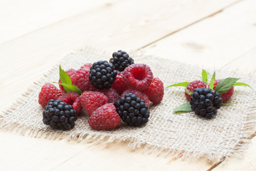 Fresh sweet red raspberry, blueberries and mint on light wooden table, selective focus