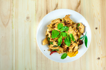Spicy Thai basil chicken ready to eat on traditional plate with wooden spoon. Top View. (Shallow aperture intended for  the aesthetic quality of the blur.)