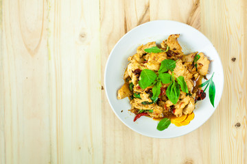 Spicy Thai basil chicken ready to eat on traditional plate with wooden spoon. Top View. (Shallow aperture intended for  the aesthetic quality of the blur.)