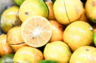 close up of a lemon cut in a half above some lemons