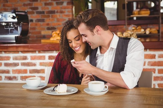  Young happy couple feeding each other with cake