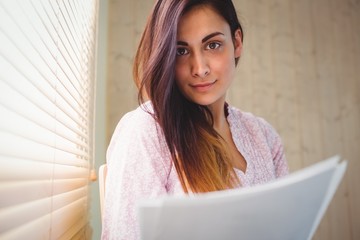 Pretty brunette reading documents beside window