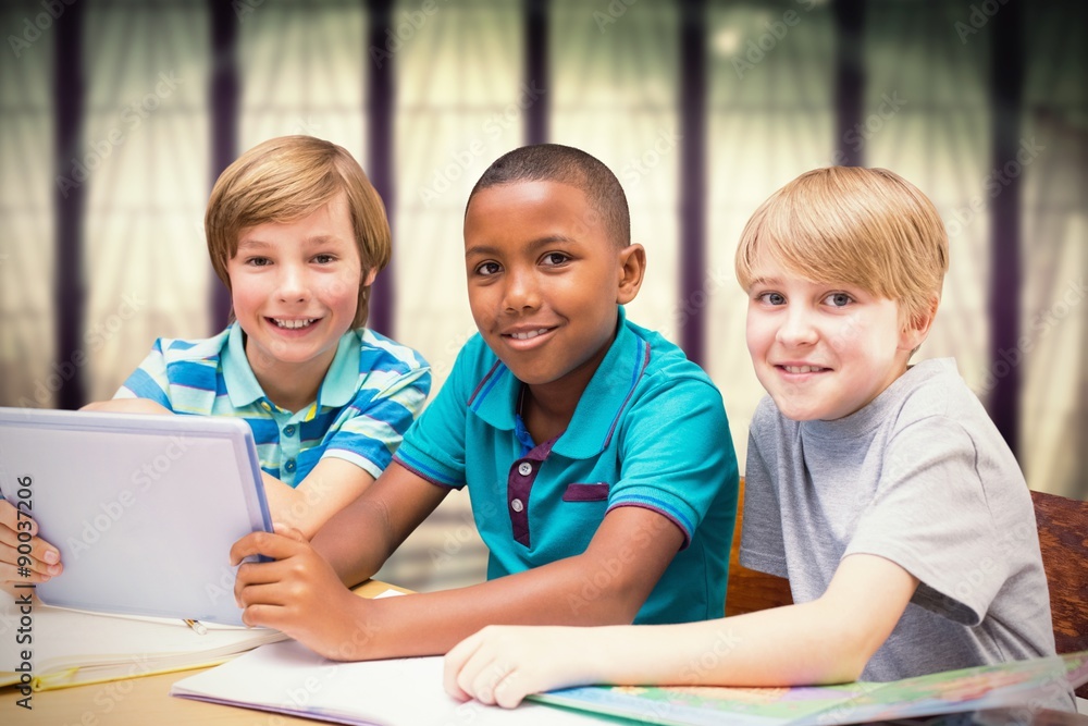 Wall mural Composite image of cute pupils using tablet computer in library