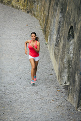 Female fit hispanic athlete running outdoor. Sporty cheerful woman training.