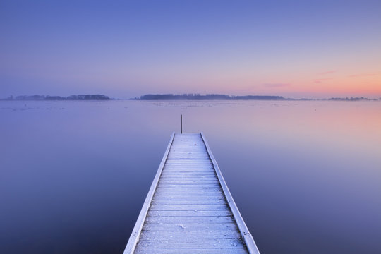 Jetty on a still lake in winter in The Netherlands