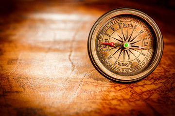 Fototapeta na wymiar Vintage compass lies on an ancient world map.