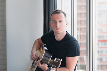 Man in denim shorts sitting next to the window with his guitar music, musician, hobby, lifestyle, hobby