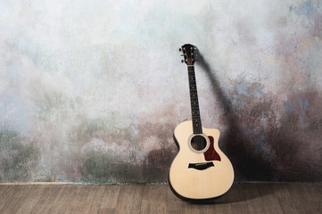 Fototapeta na wymiar The guitar stands near the wall in the style of grunge, music, musician, hobby, lifestyle, hobby