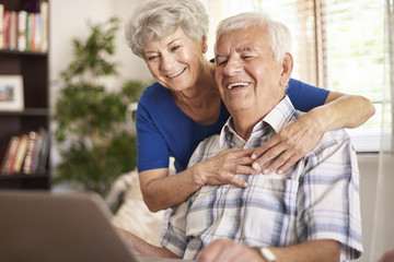 Happy grandparents using their digital laptop