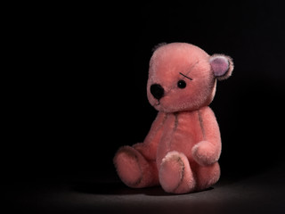 Cute little pink teddy bear on a black background