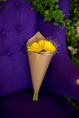 Bouquet of yellow gerbera wrapped in kraft paper lying on a chair