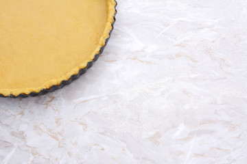 Baking tin lined with pastry on worktop