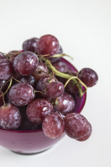 Fresh red grapes in a purple bowl