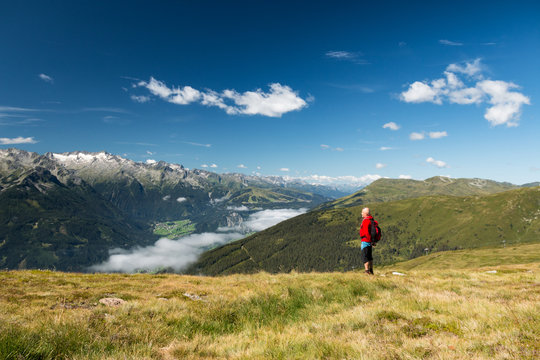 Senior With Backpack Hiking In Alpine Mountains With Scenery View