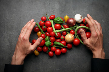 Man hands taking fresh vegetables on grey kitchen table