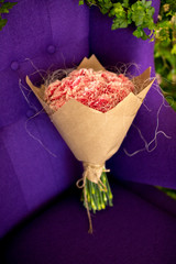 Bouquet of carnation wrapped in kraft paper lying on a chair