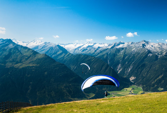 paraglider starting flight in austrian mountains on wildkogel near kaprun with glacier scenic view
