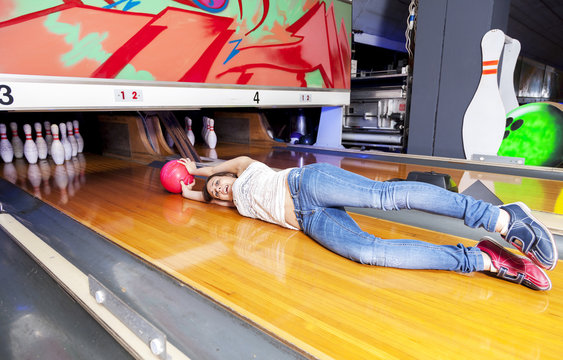 Young Woman Sliding Down A Bowling Alley