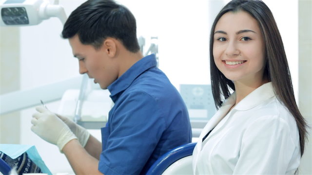 Girl-assistant sitting next to a dentist and teeth smile