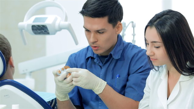 Dentist beside the girl-intern at the table with dental