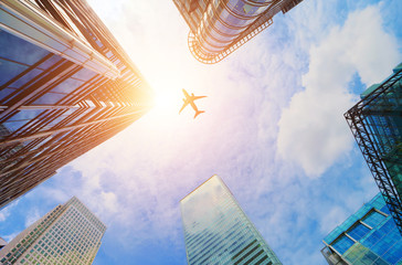 Airplane flying over modern business skyscrapers. Transport, travel.