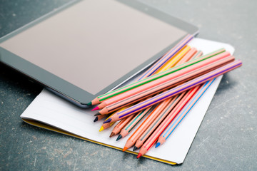 colored pencil , blank notebook and computer tablet