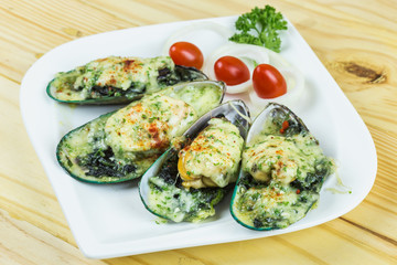 Mussels under cheese on wooden table