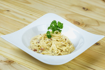 Spaghetti Cabonara with creamy sauce on wooden table