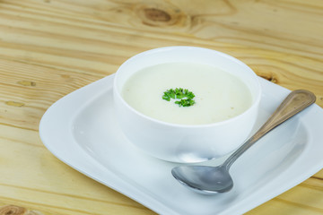 Cream soup in white bowl on wooden table