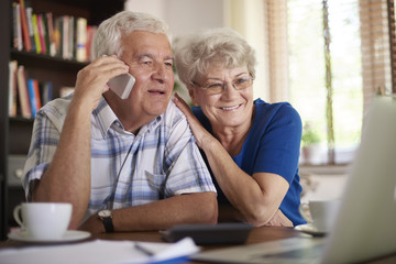 Smiling senior couple making deal via telephone