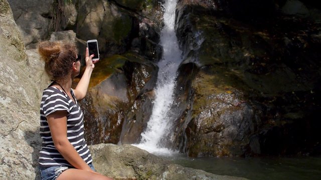 Woman Taking Photo of Waterfall Outdoors with Phone