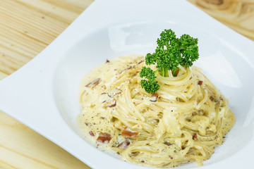 Spaghetti Cabonara with creamy sauce on wooden table