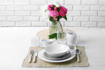 Obraz na płótnie Canvas Beautiful table setting with flowers in vase on brick wall background