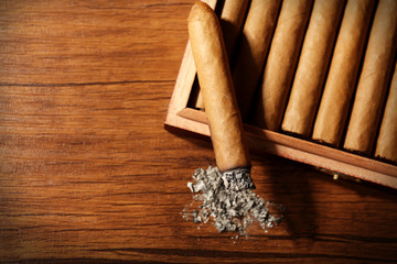 Cigars and burnt one with ash on wooden table, top view