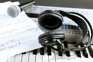 Headphones with music notes and microphone on synthesizer close up
