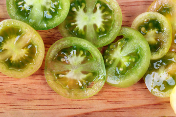 Fototapeta na wymiar Slices of green tomato on wooden background