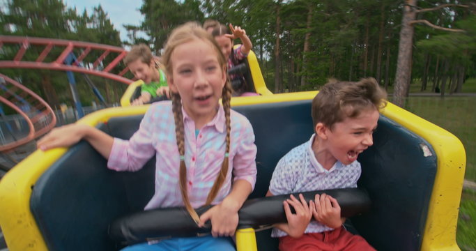 Group of kids shouting while riding a roller coaster 