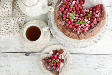 Piece of cake with chocolate Glaze and raspberries on color wooden background