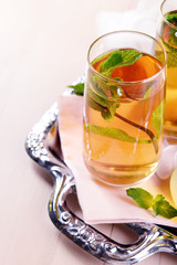 Glass of apple juice with fruits and fresh mint on table close up