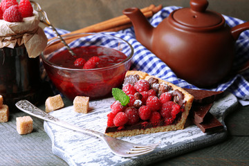 Piece of tart with fresh raspberries, on wooden background