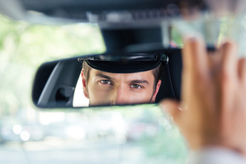 Male chauffeur looking at his reflection in a mirror