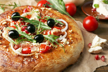 Greek homemade pizza with ham,onion, roasted tomato, creamy feta on wooden table background