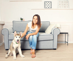 Portrait of young woman and her malamute dog in room