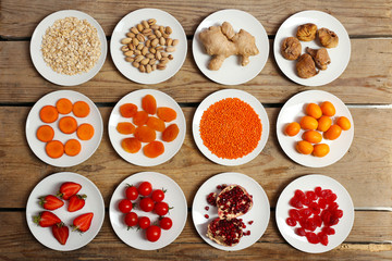 Different products on saucers on wooden table, top view