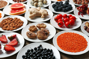 Different products on saucers on wooden table close up