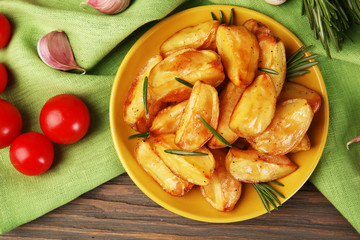 Baked potato wedges on wooden table, top view