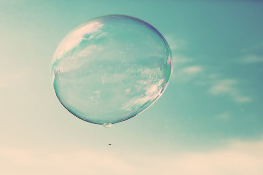 One clean soap bubble flying in the air, blue sky. Vintage