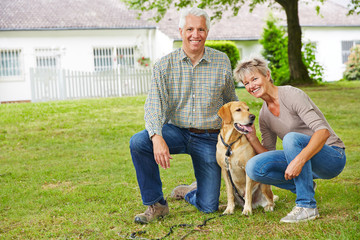 Zwei Senioren mit Hund vor Haus