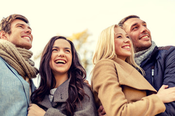 group of smiling men and women in autumn park