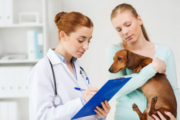 woman with dog and doctor at vet clinic